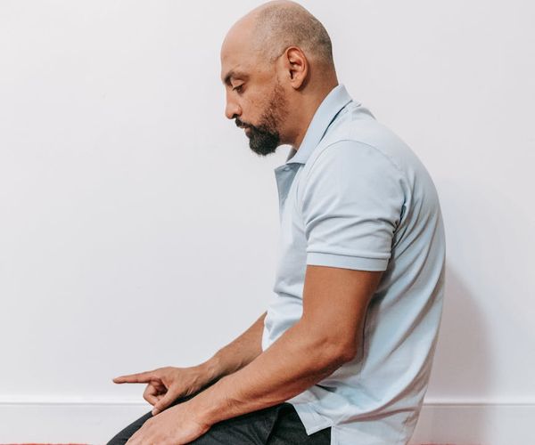Person sitting in a calm, meditative yoga pose indoors.